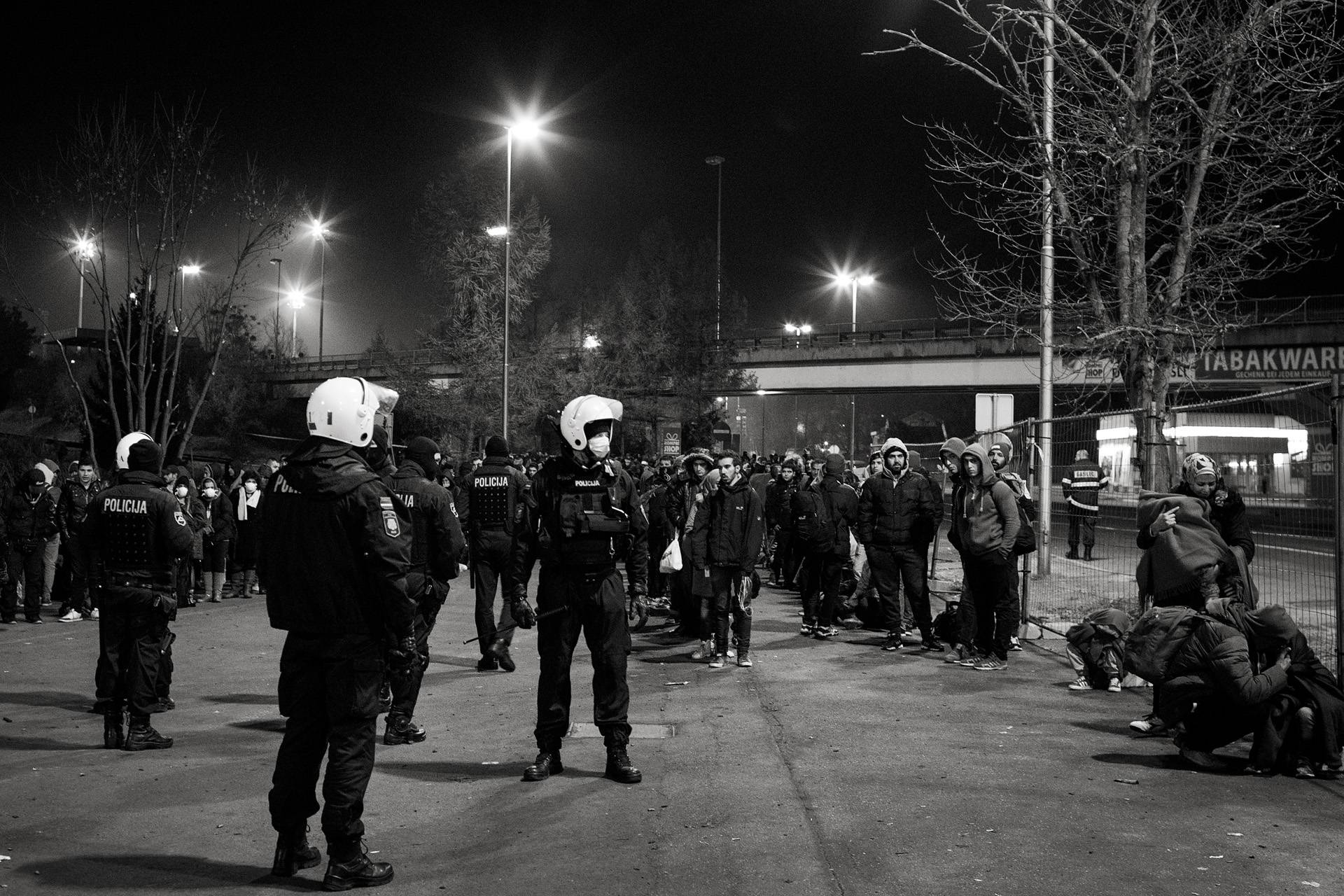 19. November 2015. Šentilj, Slowenien. Slowenische Polizeikräfte bewachen eine Gruppe Geflüchtete am Grenzübergang nach österreichischem Spielfeld.
