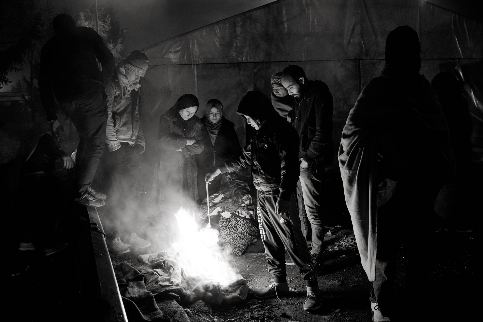 19. November 2015. Šentilj, Slowenien. Geflüchtete, die über Nacht im „Niemandsland“ festgesetzt worden sind, brennen Textilien um sich zu wärmen.